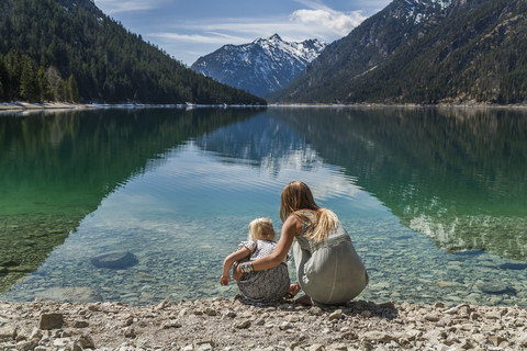 Österreich, Tirol, Plansee, Mutter und Tochter am Seeufer, lizenzfreies Stockfoto