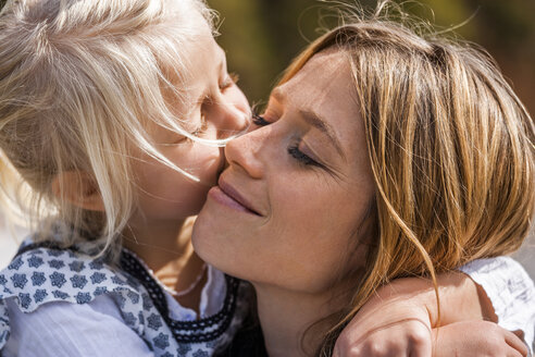 Girl hugging and kissing smiling mother - TCF004606