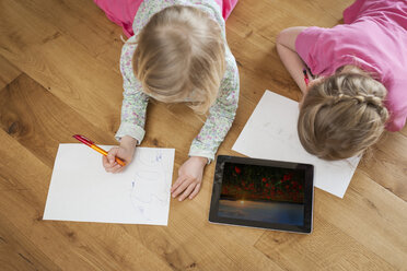 Zwei Schwestern mit digitalem Tablet und Papierblättern auf dem Boden - PAF001319