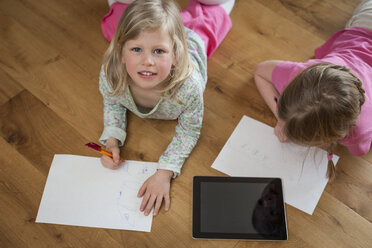 Zwei Schwestern mit digitalem Tablet und Papierblättern auf dem Boden - PAF001320