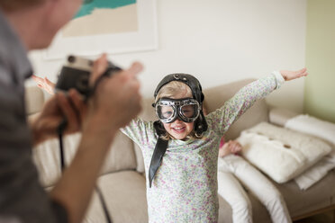 Father taking picture of girl pretending to fly - PAF001322