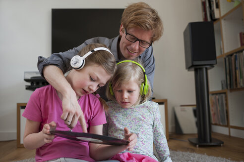 Father with two daughters wearing headphones showing record - PAF001314