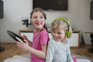 Two sisters with record and headphones at home - PAF001328