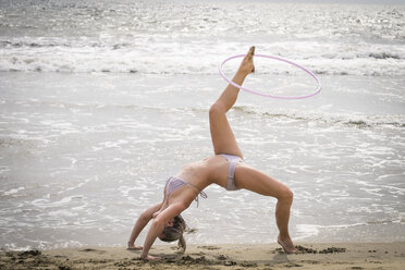 Mexiko, Riviera Nayarit, junge Frau übt mit Hula-Hoop-Reifen an der Strandpromenade - ABAF001664