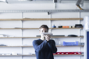 Technician in workshop examining piece of metal - SGF001528