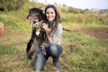 Smiling woman holding dog outdoors - GEMF000221