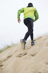 Spain, Galicia, Valdovino, man running up a dune on the beach - RAEF000145