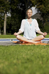 Blonde woman practising yoga in her garden - TOYF000001