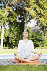 Blonde Frau übt Yoga in ihrem Garten - TOYF000021