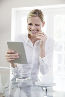 Eine Frau im mittleren Erwachsenenalter benutzt ein digitales Tablet - TOYF000026