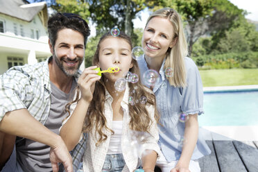 Glückliche Familie am Pool beim Spielen mit Seifenblasen - TOYF000037