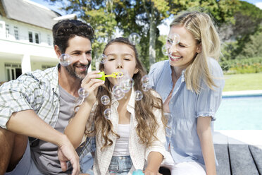 Glückliche Familie am Pool beim Spielen mit Seifenblasen - TOYF000038