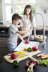 Brother and sister washing vegetables in kitchen - TOYF000045