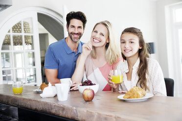 Smiling family sitting at breakfast table - TOYF000048