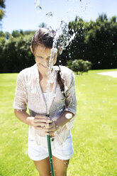 Young girl splashing water with garden hose - TOYF000062