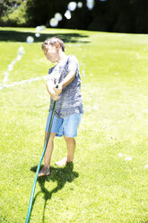 Junge spritzt Wasser mit Gartenschlauch - TOYF000064