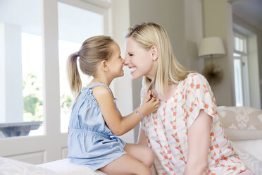 Mother and daughter sitting on sofa, rubbing noses - TOYF000106