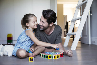 Vater und Tochter spielen mit Bauklötzen auf dem Boden - TOYF000111