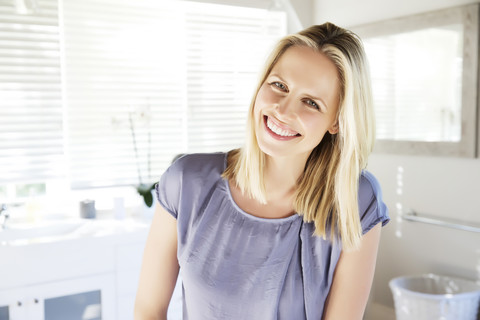 Blonde Frau steht im Badezimmer, lizenzfreies Stockfoto