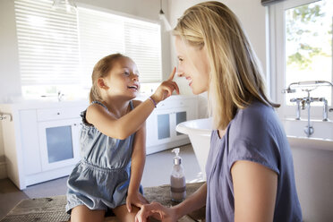 Mother and daughter in bathroom applying face cream - TOYF000120