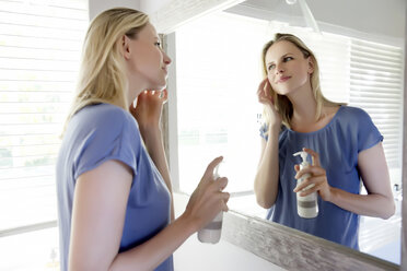 Frau im Badezimmer trägt Hautcreme auf - TOYF000122