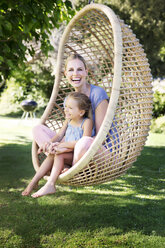 Mother and daughter relaxing in hanging chair - TOYF000124