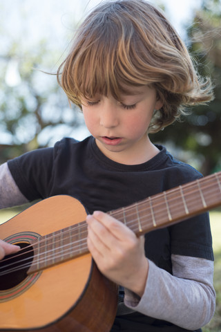 Kleiner Junge spielt akustische Gitarre, lizenzfreies Stockfoto