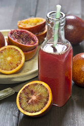 Glass bottle of blood orange juice, whole, sliced and squeezed blood oranges - YFF000408