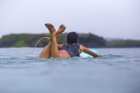 Indonesien, Insel Lombok, Frau entspannt auf Surfbrett im Wasser - KNTF000015