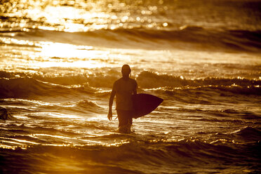 Indonesia, Bali, man with surfboard at twilight - KNTF000016