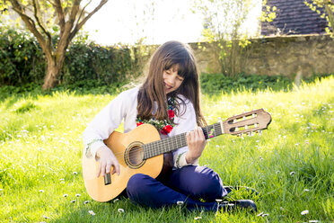 Lachendes Mädchen, das auf einer Wiese sitzt und Gitarre spielt - LVF003226