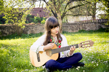 Mädchen sitzt auf einer Wiese und spielt Gitarre - LVF003227
