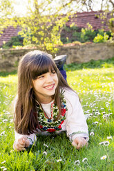 Porträt eines lächelnden Mädchens, das auf einer Wiese liegt - LVF003229