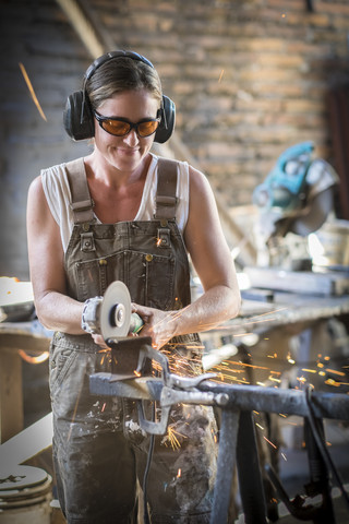 Schweißerin bei der Arbeit in einer Metallwerkstatt, lizenzfreies Stockfoto