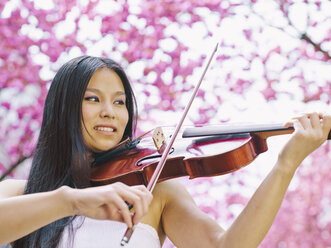 Porträt einer Violaspielerin vor einem blühenden Kirschbaum - MADF000189