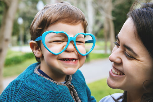 Porträt eines kleinen Jungen, der mit einer herzförmigen Brille Grimassen schneidet - GEMF000222