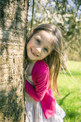 Portrait of smiling girl besides tree trunk - SARF001743