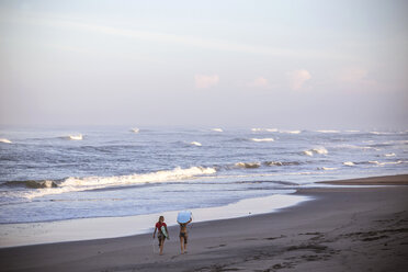 Indonesia, Bali, two women carrying surfboards on the beach - KNTF000004