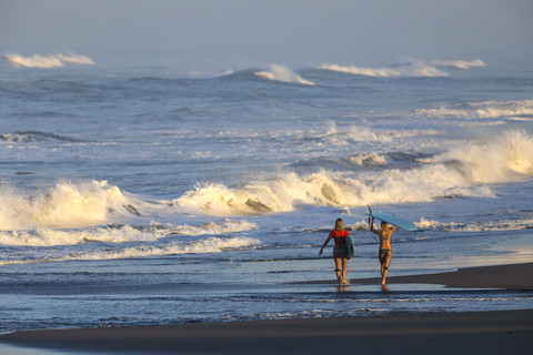 Indonesien, Bali, zwei Frauen mit Surfbrettern an der Strandpromenade, lizenzfreies Stockfoto