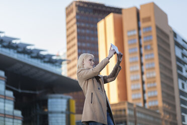 Germany, Berlin, young woman taking a selfie with phablet - MMFF000846