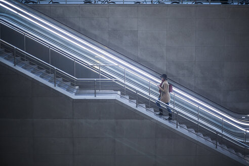 Young woman with coffee to go walking upstairs - MMFF000839