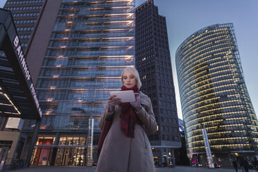 Deutschland, Berlin, junge Frau mit Mini-Tablet am Abend am Potsdamer Platz - MMFF000849