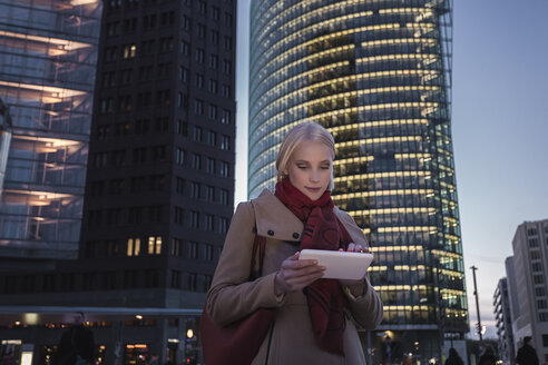 Deutschland, Berlin, junge Frau mit Mini-Tablet am Abend am Potsdamer Platz - MMFF000850