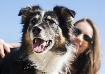 Glückliche junge Frau mit Hund im Freien - UUF003925