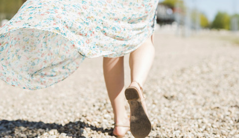 Frau geht am Kiesstrand spazieren, lizenzfreies Stockfoto