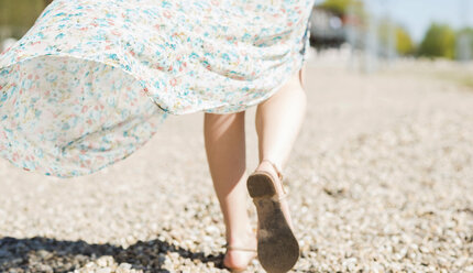 Woman walking on shingle beach - UUF003868