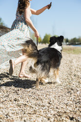 Frau geht mit Hund im Sommer im Freien spazieren - UUF003927