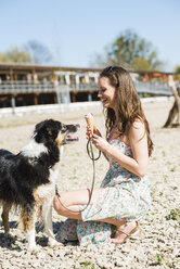 Junge Frau mit Hund und Eiswaffel im Freien im Sommer - UUF003930