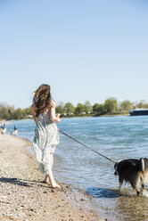 Germany, Mannheim, young woman walking with dog at River Rhine - UUF003931