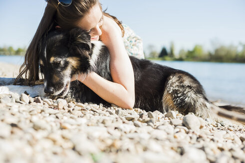 Deutschland, Mannheim, junge Frau kuschelt mit Hund am Rhein - UUF003936